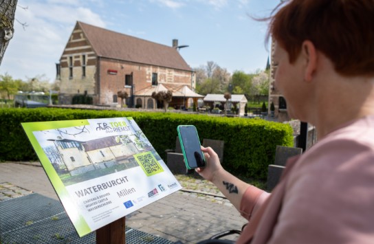 Een vrouw scant een informatiebord over de Waterburcht in Millen. (vergroot foto)